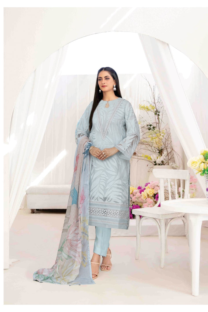 Woman in a light blue traditional outfit with a floral dupatta in a decorated room.